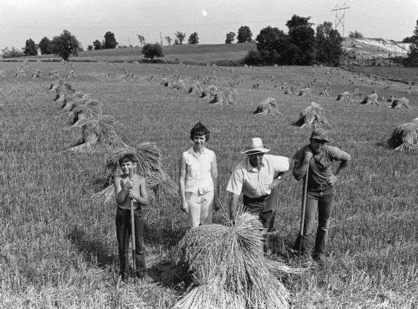 "Gerald and Grace Batzler with sons, Roger and Thomas, pose in a field dotted with shocks of grain."