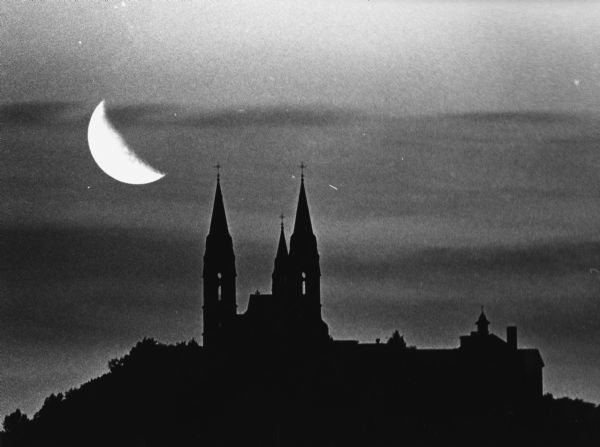 "The spires of Holy Hill appear in the distance at sundown as some Camelot in the sky. The long, 500 mm lens emphasizes the size of the church and the low-hanging September moon."