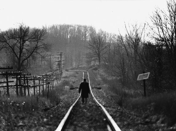 "When a fugitive escaped from the Winnebago County Courthouse, Oshkosh, he headed south on Hwy 41 to Allenton where he stole two pistols from a rural home. He then fled north on foot on the Soo Line tracks into the Theresa Marsh. This is a recreation showing a shadowy figure walking along the tracks."