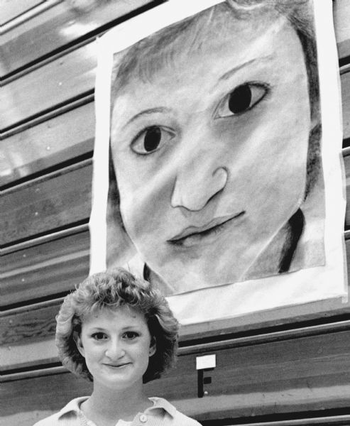 "Karen Schmidt poses next to a self-portrait."