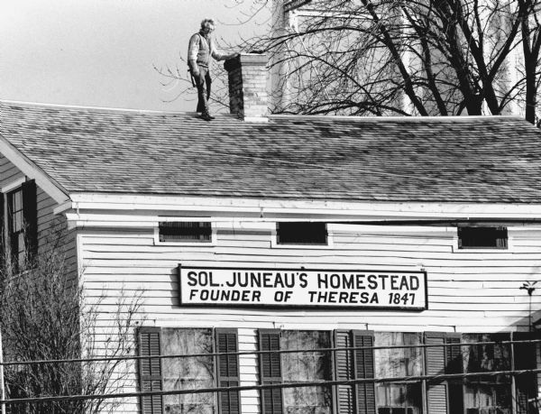 "A workman was photographed as final touches were being completed on the reshingled roof of the Solomon Juneau Home."