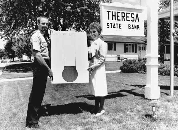 "Suzanne Erdman of Theresa State Bank and Fireman Chuck Trauba hold a sign showing progress of Theresa Fire Department's Jaws of Life Fund Raiser."