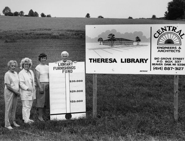 "Theresa library board members, Peggy Langenfeld, Sandy Merchant, Betty Bodden, and Ralph Widmer pose with a fund-raiser sign."