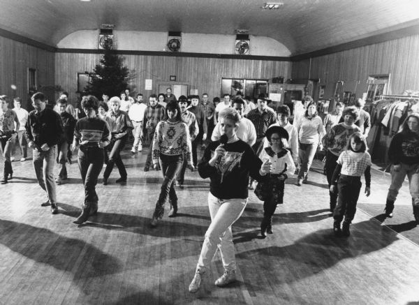 "On a Sunday evening at G & Z's Hall, country and western line dancers step out smartly to the music."