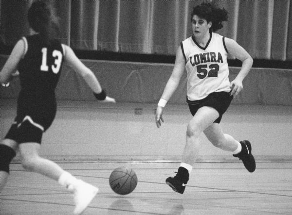 "In Flyway Conference basketball at Lomira, Julie Benter dribbles against Oakfield. Benter, a senior honor student, is one of the leading scorers in the conference and also a standout in track (discus & shot put)."