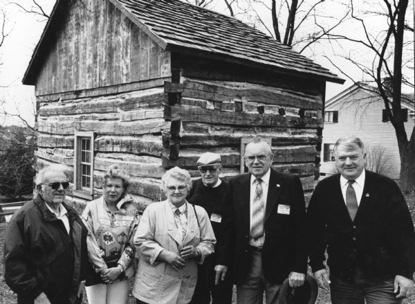 "Historical Society members tour the newly-moved log building on the Society grounds. John Bodden and Les Beck are 4th and 5th from the left."
