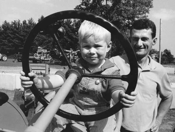 "Matthew Bodden, age 3, with his father, Todd, pretends to operate a tractor at the Antique Tractor Show at Theresa Firemen's Park."