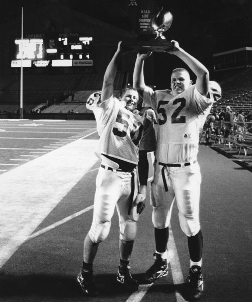 "When the Mayville Cardinals defeated Baldwin-Woodville for the WIAA State Football Championship, Dave Vanden Bloom (50) and Mike Lance (52) proudly displayed the trophy."