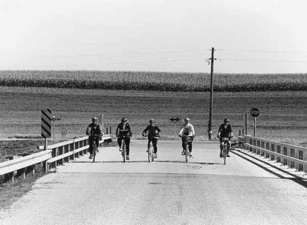 "Bike riders cross the Rock River near the intersection of AY & Gill Road."