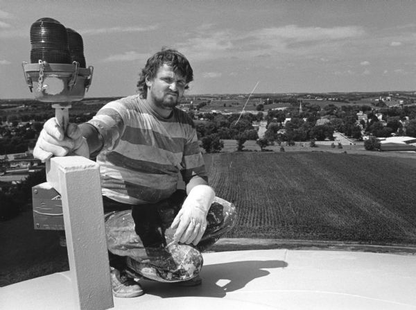 "Painter Pat Calkins of Merrillan, WI poses on the top of the new water tank."