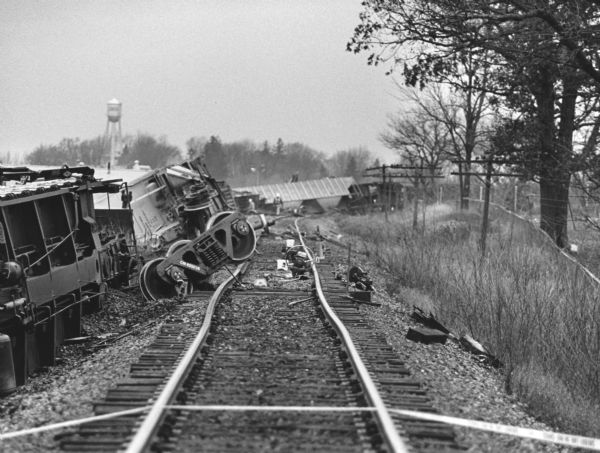 "Looking north along this section of track, one can see the overturned car's wheels, and debris after the derailment. The visible bend in the tracks was caused by the derailment."