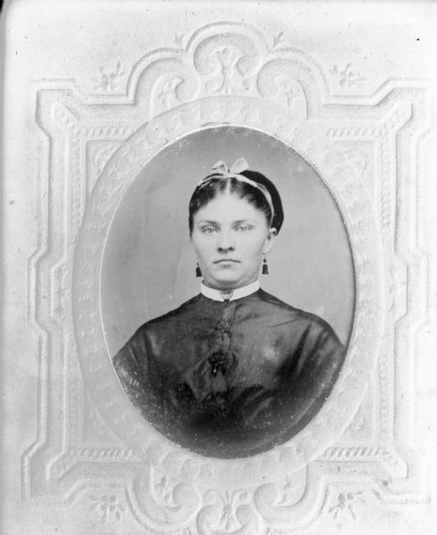 Copy negative of possibly a tintype. Quarter-length oval portrait. The sitter is possibly Miss Prilvits. She is wearing earrings and has a ribbon in her hair.