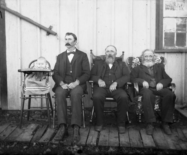 Outdoor group portrait of four generations of Krueger men. Sitting from left to right are: Edgar, Alex, William, and August.