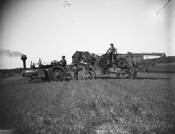Three Kuckkahn Brothers standing and siting on their Altman-Taylor Engine, Separator, and Threshing Rig.