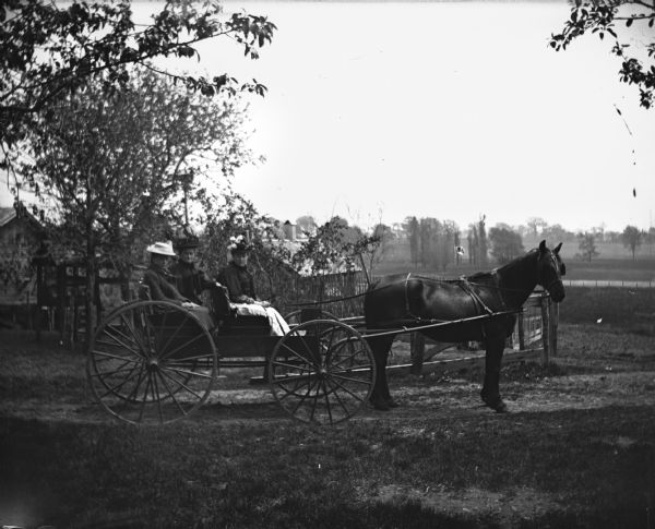 View of Hattie Braemer, Florentina Krueger, and Sarah Krueger on a horse-drawn buggy, ready to go to the circus.