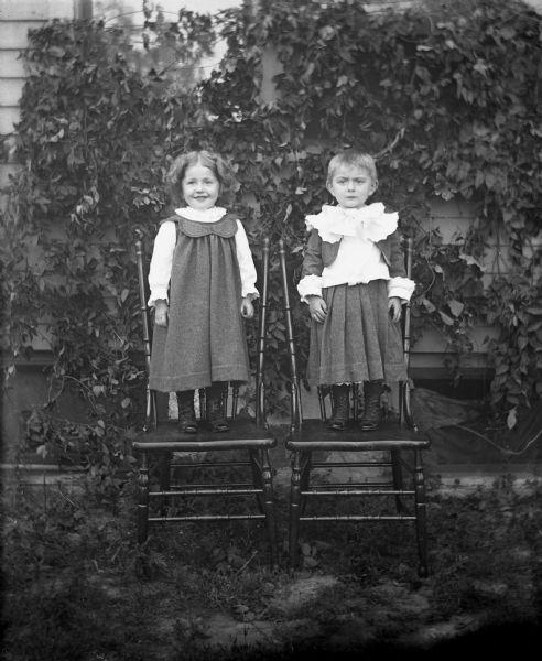 Portrait of Jennie and Edgar Krueger standing on chairs.