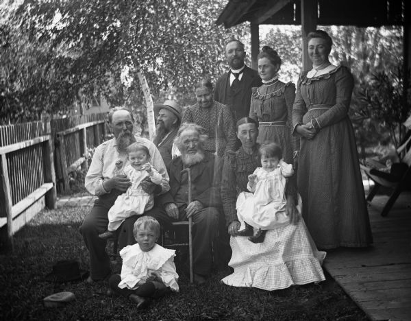 Charles Goetsch and Krueger family. Rexford Krueger (on lawn), August Krueger, Edgar (on lap), with William Krueger, (holding cane), Charles Goetsch (looking up), Mrs. Charles Amelia Goetsch, Henry Krueger, Mary Krueger holding Jennie, Mrs. Alex Krueger and Sarah Krueger Bhend.