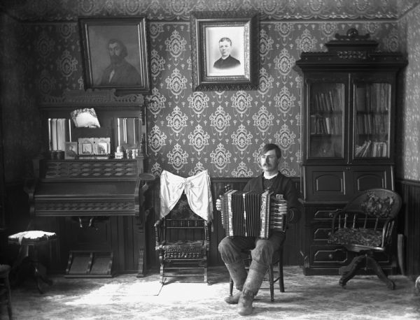 Portrait of Herman Bentert with an accordion in Bentert's sitting room.