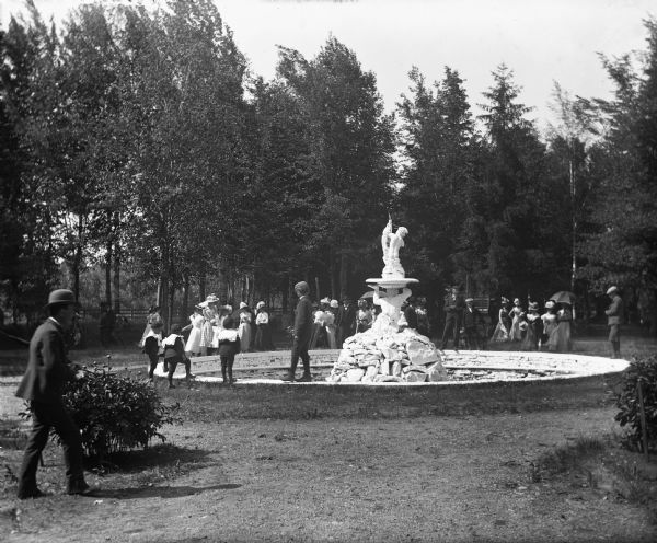 Children and adults standing near a figural fountain on Concordia, later Tovoli, Island.