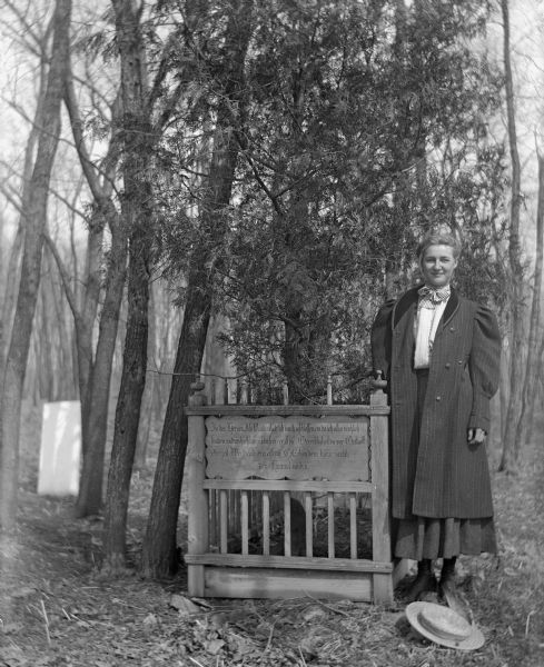An unidentified woman standing next to an engraved wooden memorial in Kripplein Christi cemetery.