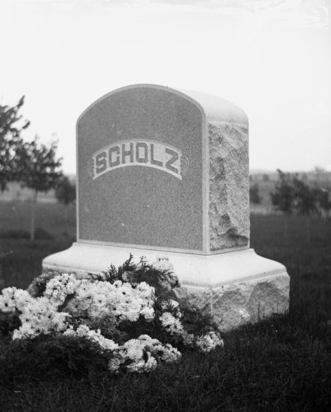 Scholz family monument located at Oak Hill Cemetery. Flower arrangements adorn the base of the headstone.