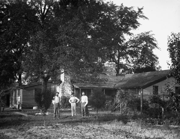 Ernst Goetsch, Paul C. Goetsch, and Alexander Krueger standing in front of the home of Paul C. Goetsch. Large trees surround the house.