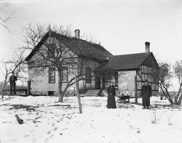 Ed, Martha, and William Wendorf posing in front of their home in the winter.