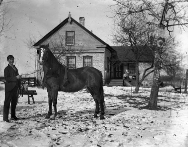 Ed Wendorf standing with his horse in front of the Wendorf home.