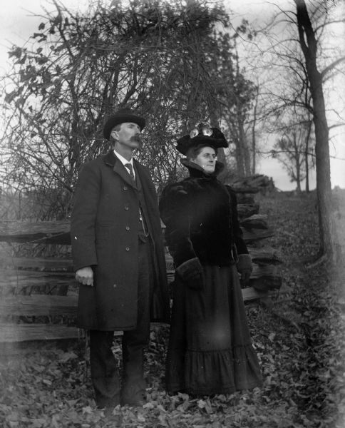 Full-length outdoor portrait of Alexander and Florentina Krueger standing in front of a split-rail fence on Loock's Hill.