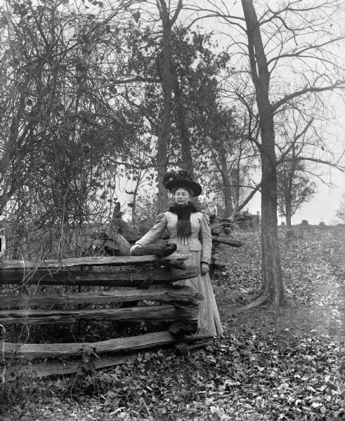 Full-length outdoor portrait of Sarah Kruger standing next to a split-rail fence on Loock's hill.