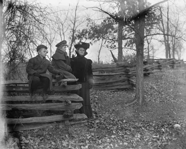 Jennie and Edgar Kruger sitting on a split-rail fence on Loock's hill with their mother, Florentina Kruger, standing beside them.