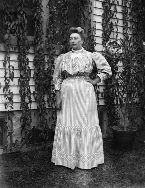 Outdoor portrait of Sarah Krueger standing next to a house with ivy.