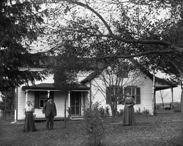Mary, August, and Sarah Krueger standing in the yard in front of their home.