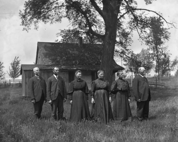 The six children of William Krueger standing in the yard in front of their father's home, all dressed in black for his funeral. They are arranged in birth order from right to left, Henry, Albert, Minnie, Bertha, Emilie,and August Krueger.