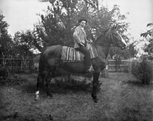 Sam Goetsch sitting atop a horse in a fenced-in yard.