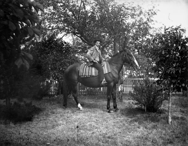 Sam Goetsch sitting atop a horse in a fenced in yard.