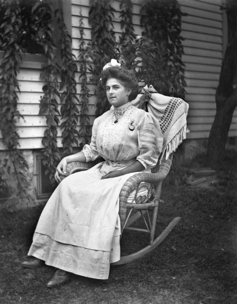 Outdoor portrait of Hattie Fels Owen sitting in a rocking chair next to the Krueger house.