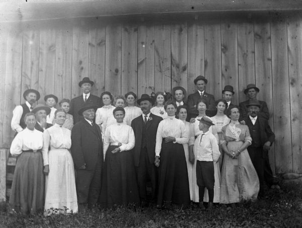 Outdoor group portrait of the extended Krueger family. There is a farm building behind them.