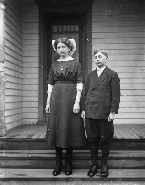 Outdoor portrait of Jennie and Edgar Krueger standing on the front porch of the Krueger home.