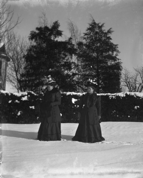 Ella and Ida Scholz standing in front of the Langholf home during winter.