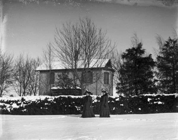 Ella and Ida Scholz standing posing in front of their home during winter.