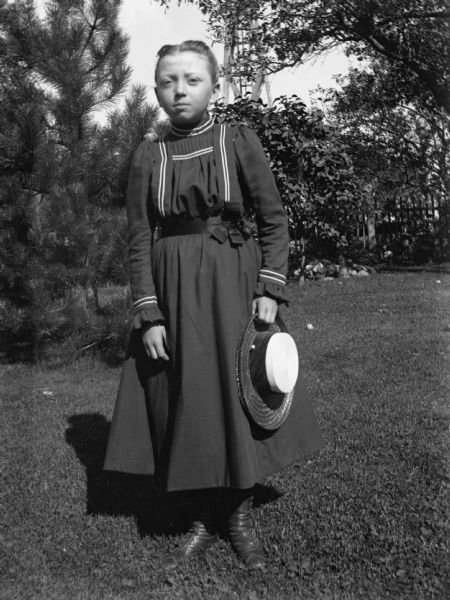 Outdoor portrait of Hedwig Ullrich standing in the yard holding her hat.