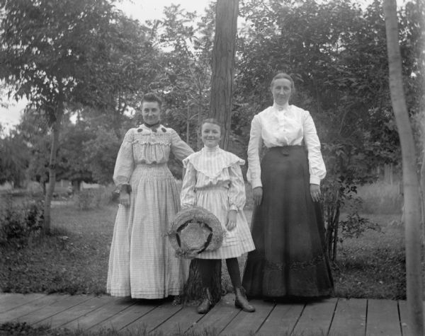 Outdoor portrait of Tillie Timel, Selma Lindeman, and Louise Timmel, cousins of Florentina Krueger, standing on a wood plank sidewalk.