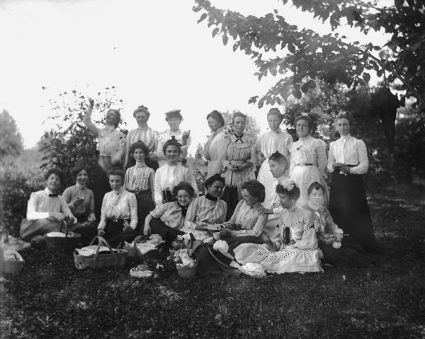 Group portrait of 19 women picnicking in Will's woods. The women are friends, neighbors, and relatives of the Krueger family. Sarah Krueger stands in the back row, second from the left.