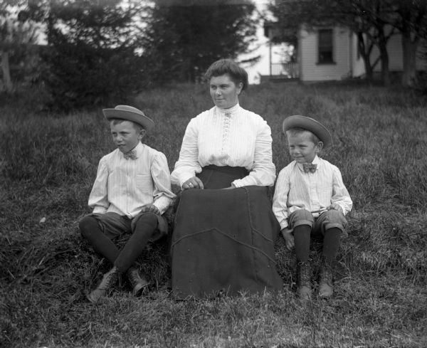 Outdoor portrait of Amanda Backhaus and her two sons, Alvin and Alex, sitting in a yard.
