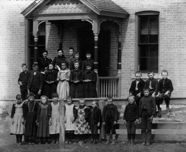 Outdoor portrait of students and teachers posing at the entrance of the Rock (?) schoolhouse for the yearly picture.