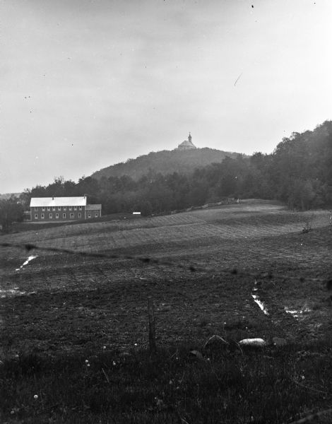 Distant view across field of Holy Hill. Below the hill is the Hillside Hotel on the left.