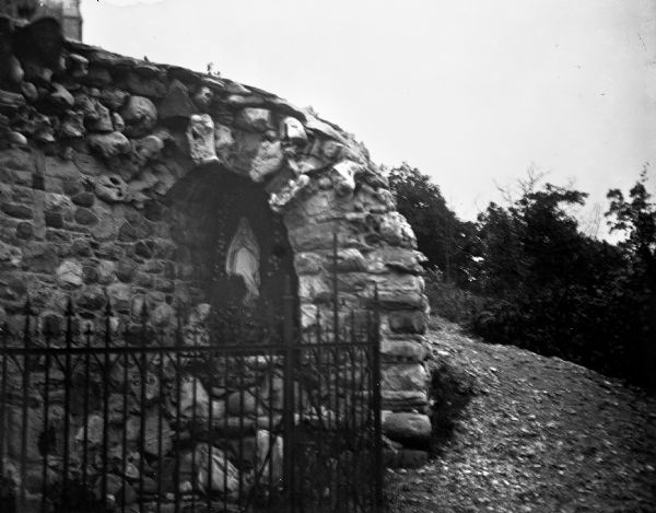 View of the grotto on Holy Hill. A statue of the Virgin Mary sits inside a stone arch inside the grotto.