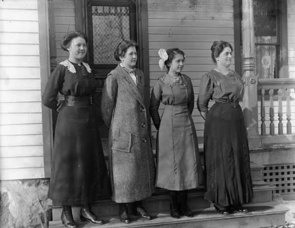 Outdoor portrait of four women posing together on the porch steps of the Krueger home. From left to right: Lilly Mallow Mass, Jennie Krueger Bruetzman, Ida Mallow Ebert, and Florentina Krueger.