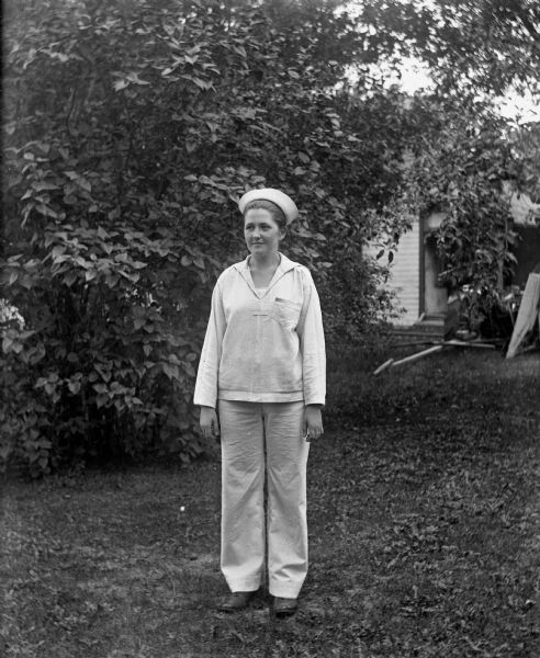 Jennie Krueger Bruetzman standing on the Krueger farm in a mans white sailor uniform.